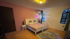 Ein Schlafzimmer mit Bett, Nachttisch, Fenster und Tür.