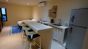 Cocina compacta con una isla central, un refrigerador y un lavamanos pequeño.