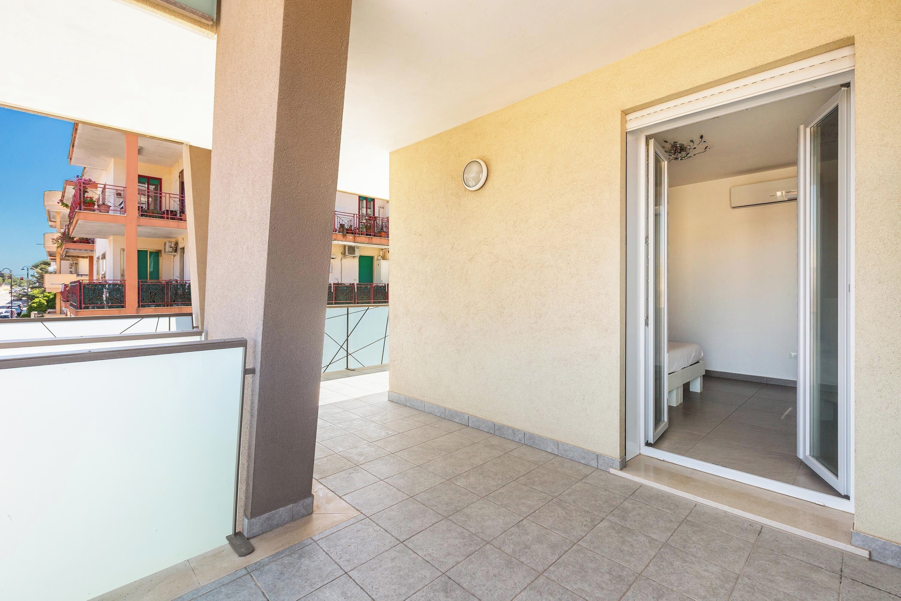 Un apartamento con balcón, puerta corredera al baño y vistas de edificios vecinos.
