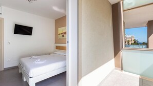 Une chambre avec un lit, un téléviseur à écran plat, un tableau et un balcon avec vue.