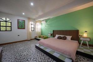 Ein Schlafzimmer mit Bett, Nachttisch, Lampe, Fenster und einem Gemälde an der Wand.