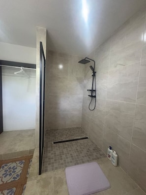 Eine Dusche mit Handbrause, Glastür und gefliestem Boden.