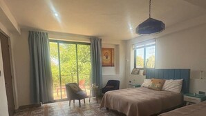 Un dormitorio con dos camas, una silla, una mesa y un ventanal con cortinas.