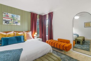 Ein Hotelzimmer mit Bett, Nachttisch, Spiegel und einem Fenster mit Vorhängen.