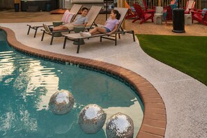 Ein Schwimmbad mit Liegestühlen und einem kleinen Gartenbereich.