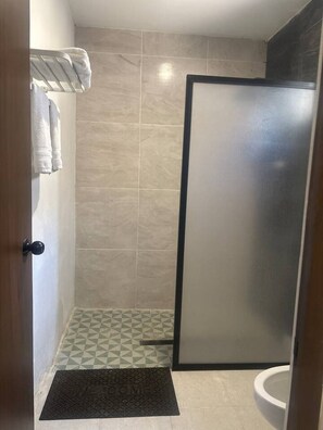Ein Badezimmer mit Dusche, Toilette und Handtuchhalter.