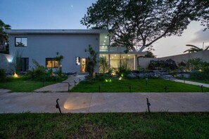A modern house with a well-maintained garden, a paved driveway, and a large tree. - Suite Estrella de Turquia (Merida)