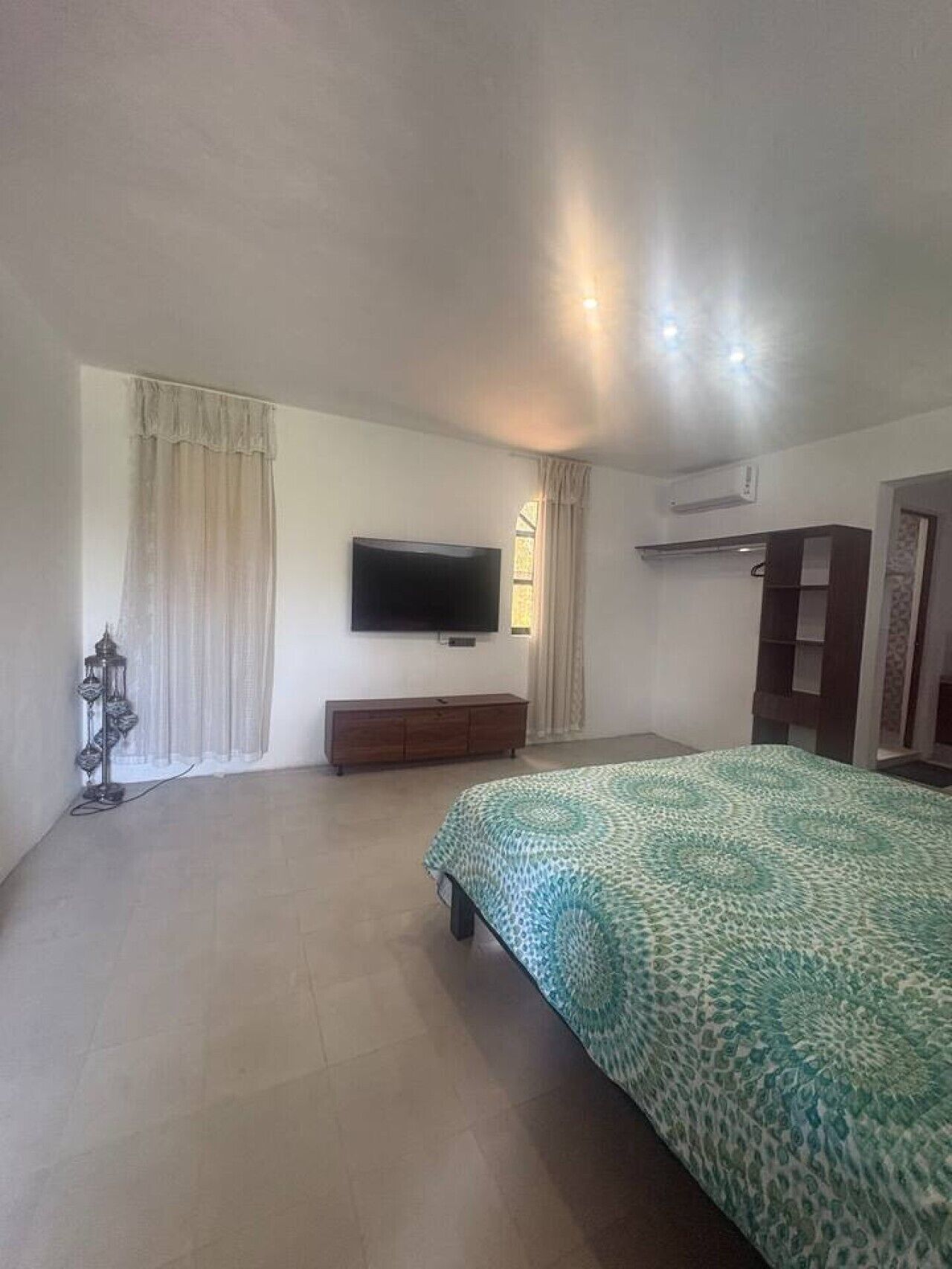 A bedroom with a bed, a TV, a dresser, and a wardrobe.