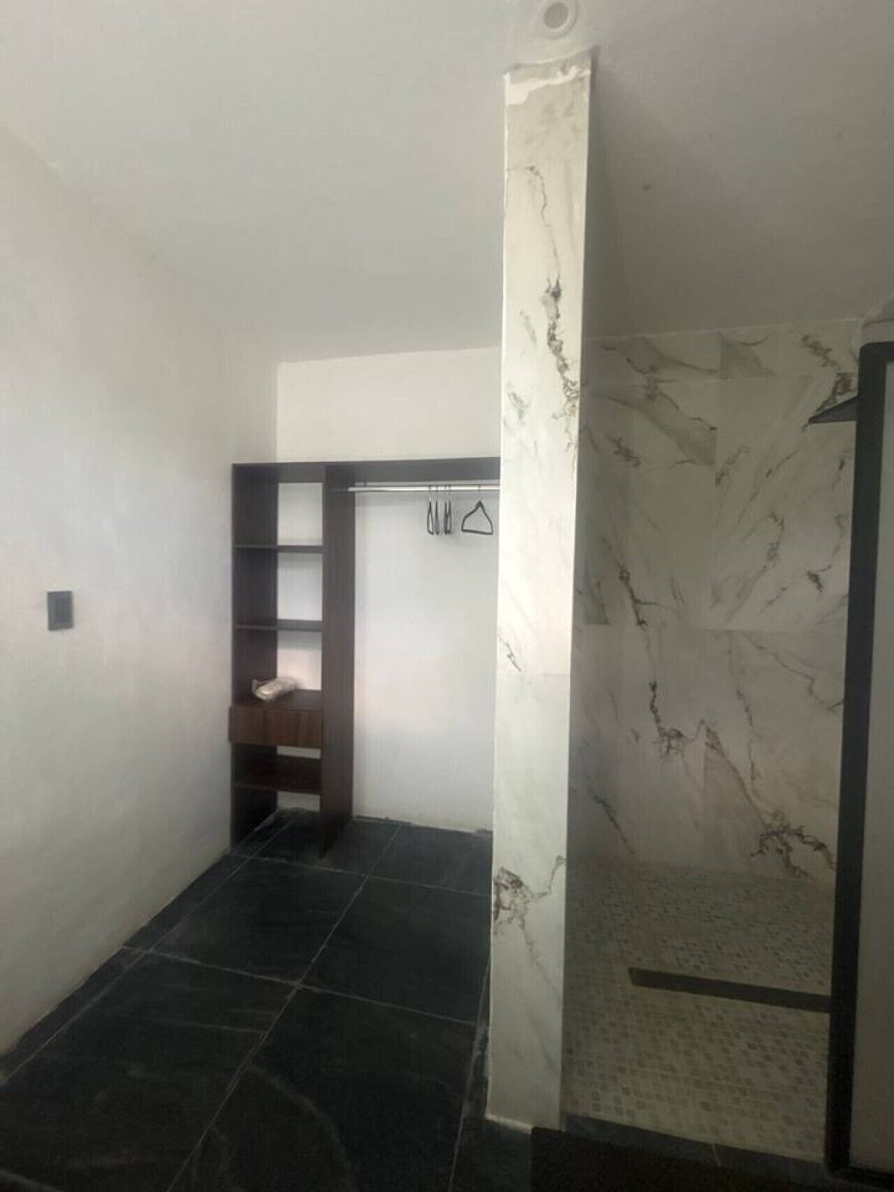 A bathroom with a shower, a towel rack, and a shelf unit.