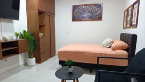 A bedroom with a bed, a small round table with a plant, a black chair, a wardrobe, and a TV on the wall. - Loft moderno norte | Ideal parejas/trabajo (Merida)