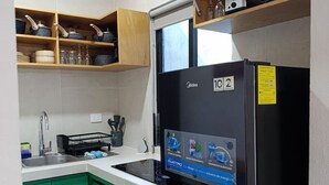A compact kitchen with green cabinets, a black refrigerator, and a wooden shelf above the sink. - Loft moderno norte | Ideal parejas/trabajo (Merida)
