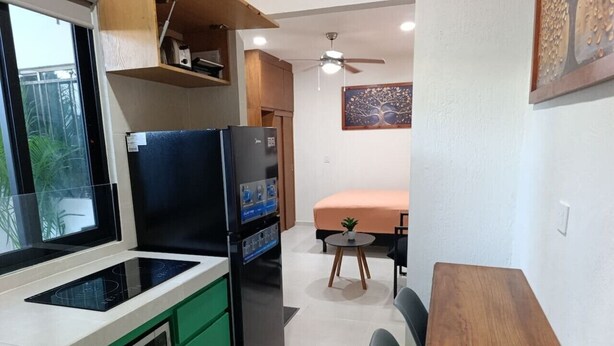 A compact kitchen with a refrigerator, stove, and sink. There is a dining area with a table and chairs. - Loft moderno norte | Ideal parejas/trabajo (Merida)