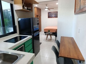 A compact kitchen with a refrigerator, stove, and sink. There is a dining area with a table and chairs. - Loft moderno norte | Ideal parejas/trabajo (Merida)