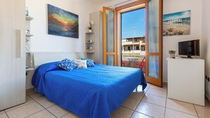 Ein Schlafzimmer mit Bett, Fernseher, Schreibtisch und Blick ins Freie.