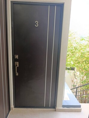 Eine dunkel gefärbte Tür mit der Nummer 3 und einem Metallgriff.