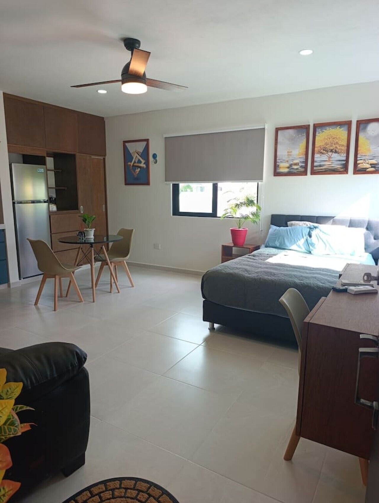 A compact living space with a kitchenette, a dining area, a bed, and a small desk.
