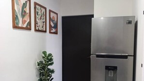 Una cocina moderna con un refrigerador de acero inoxidable, una planta en maceta y arte abstracto en la pared.