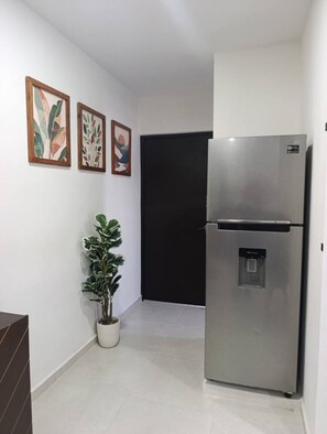 Una cucina moderna con frigorifero in acciaio inossidabile, una pianta in vaso e arte astratta appesa al muro.