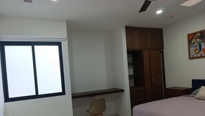 Un dormitorio con cama, escritorio, silla, armario y ventana.