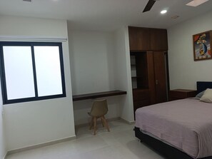 Une chambre à coucher avec un lit, un bureau, une chaise, une armoire et une fenêtre.