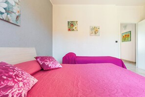 Une chambre à coucher avec un grand lit, deux oreillers, une table de chevet et deux tableaux accrochés au mur.