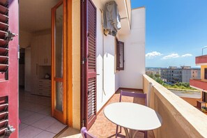 Un balcon avec une table et des chaises, une porte coulissante et une vue sur des bĂątiments au loin.