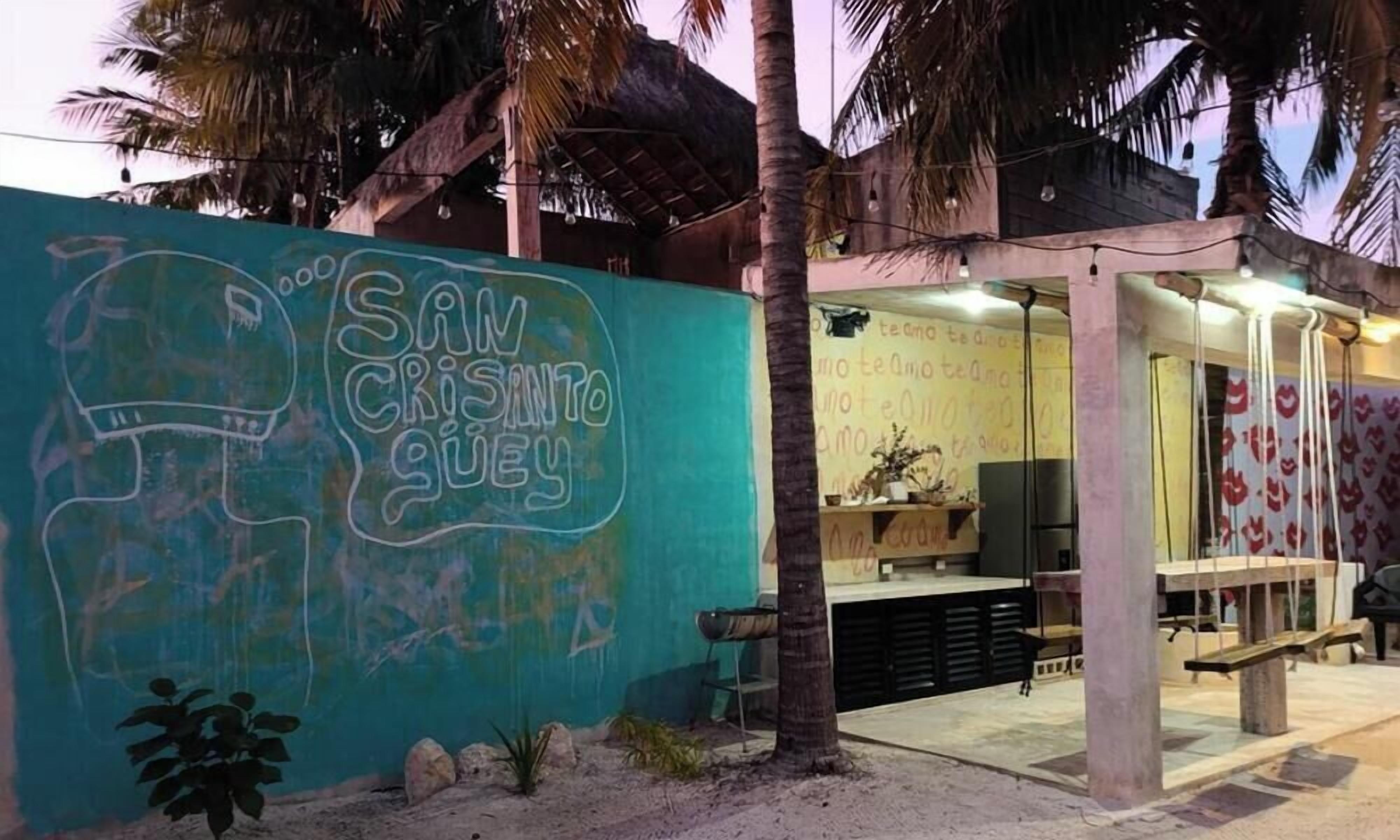 Un bâtiment situé en bord de mer, orné de graffitis, avec des palmiers et un toit de chaume.