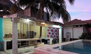 A building with a pool, a covered outdoor area, and a wall with red lips pattern.