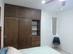 Ein Schlafzimmer mit einem Bett, einem Holzschrank, einem Stuhl und einem Spiegel an der Wand.