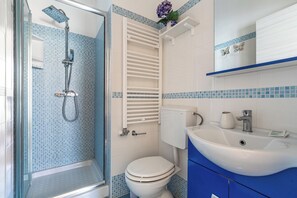 A bathroom with a shower, toilet, sink, and blue-tiled walls. - B&B Girasole - Camera Doppia (Gallipoli)