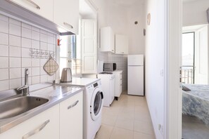 Une cuisine compacte équipée d’un lave-linge, d’un four à micro-ondes et d’un réfrigérateur.