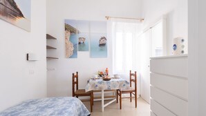 Un dormitorio con cama, una mesa con sillas, cómoda y decoración en la pared.