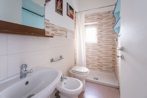 Une salle de bain équipée d’un lavabo, d’un bidet, de toilettes et d’une douche.