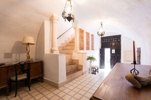 Ein Zimmer mit Treppe, Schreibtisch, Stuhl, Lampe und einem Tisch mit einem Teddybär.