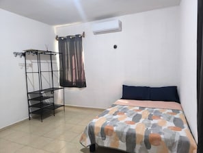Une chambre à coucher comprenant un lit, une étagère en métal, un rideau et un appareil de climatisation.