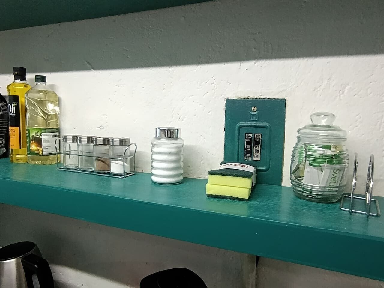 Een blauwgroen plankje met verschillende items, waaronder flessen, een witte bak, een groene doos en een pot.