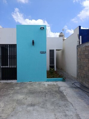 Een gebouw met een turquoise gevel, een zwart hek en een kleine tuin.