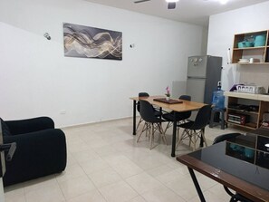 A compact living space with a dining area, a kitchenette, and a black sofa.