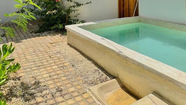 Ein Innenhof mit Schwimmbad, Holztür und Lichterketten.
