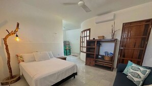 Ein Schlafzimmer mit einem Bett, einem Schlafsofa, einem Holzschrank und einer Stehlampe.