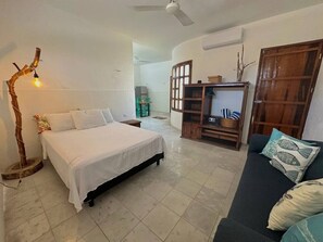 A bedroom with a bed, a sofa, a wooden cabinet, and a floor lamp. - Disfruta Chicxulub/2 Recamaras/4 personas (Chicxulub)