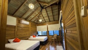 Una cabaña de madera con dos camas, una silla, una mesita y una ventana con vistas.