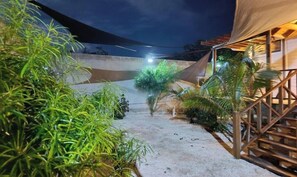 A pathway leading to a building with a covered area and a staircase.