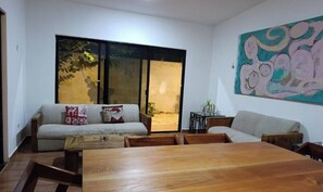 A living room with a sofa, a wooden coffee table, and a painting on the wall.