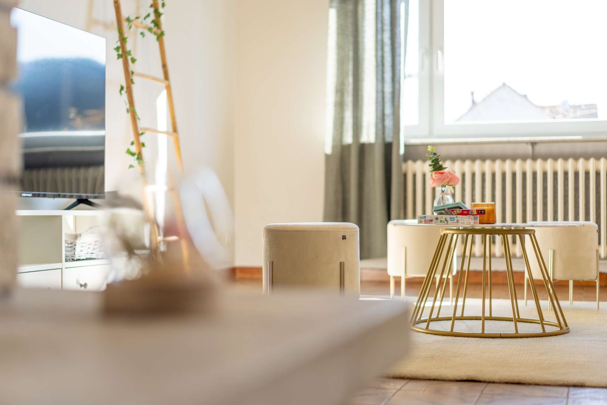 Ein modernes Wohnzimmer mit einer Couch, einem Couchtisch und Blick auf eine Stadtlandschaft durch große Fenster.
