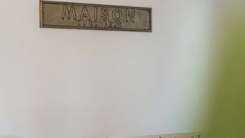 Un letrero en la pared que dice 'MAISON DU BONHEUR' y una mesa blanca con una mesa de fútbol.