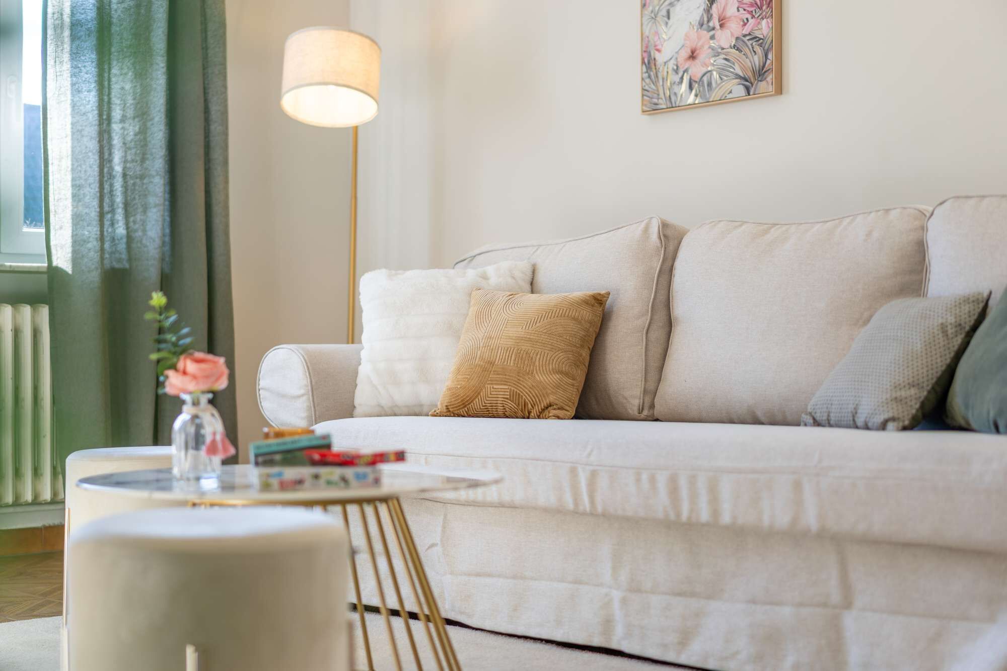 A living room with a sofa, a round coffee table, a floor lamp, and a painting on the wall.