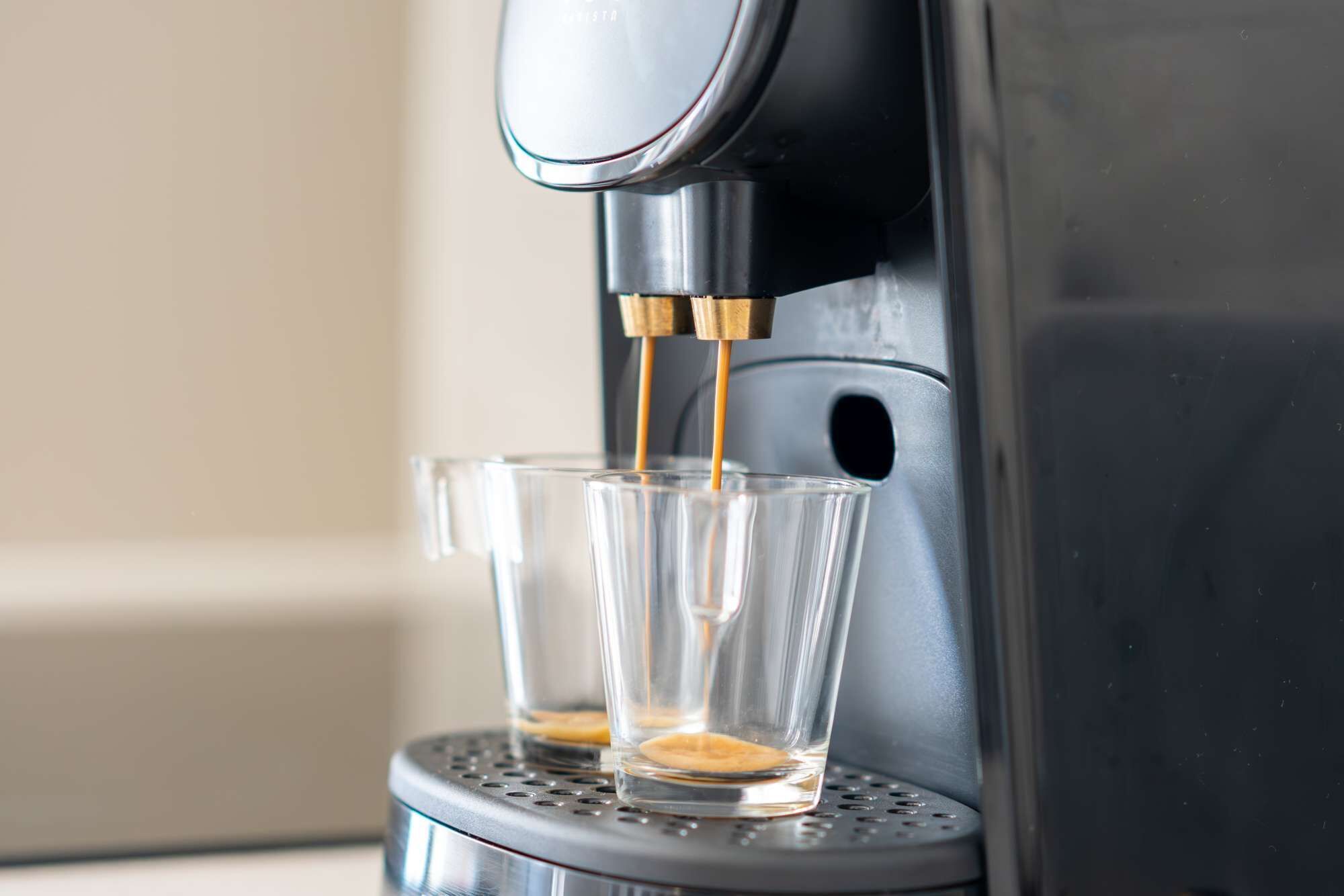 Een koffieapparaat schenkt koffie in twee glazen.