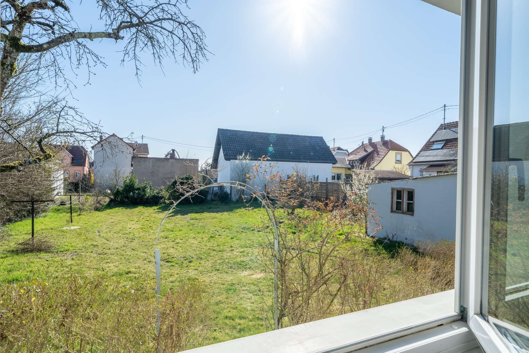 Un quartiere residenziale con case, un giardino erboso e cielo sereno.