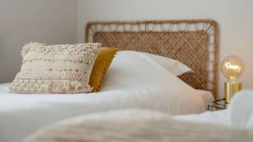 Cama com cabeceira de tear, almofada de macramé e uma almofada amarela mostarda, além de um abajur.
